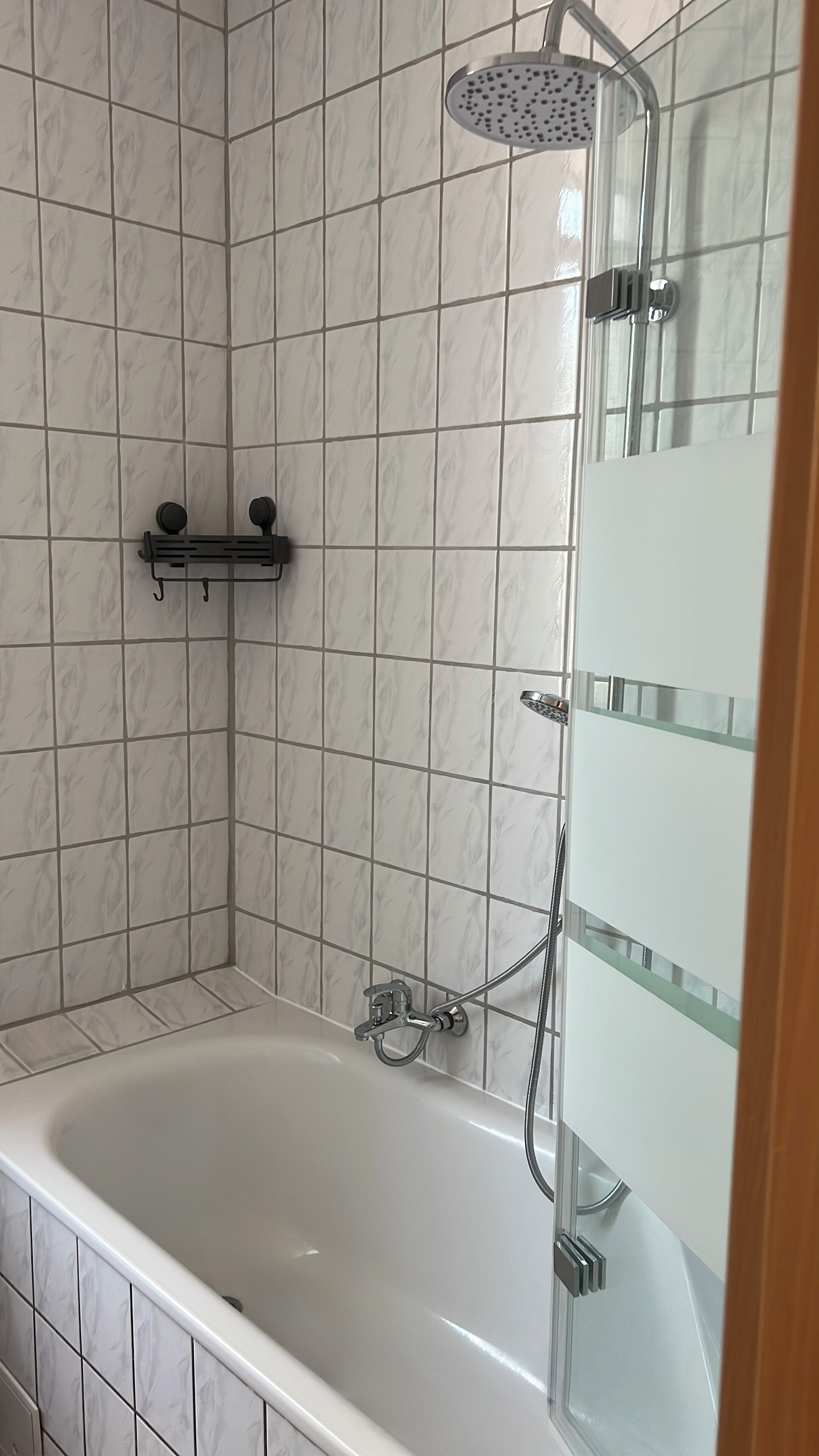 A bathroom with a bathtub, a shower head, and a glass-enclosed shower.