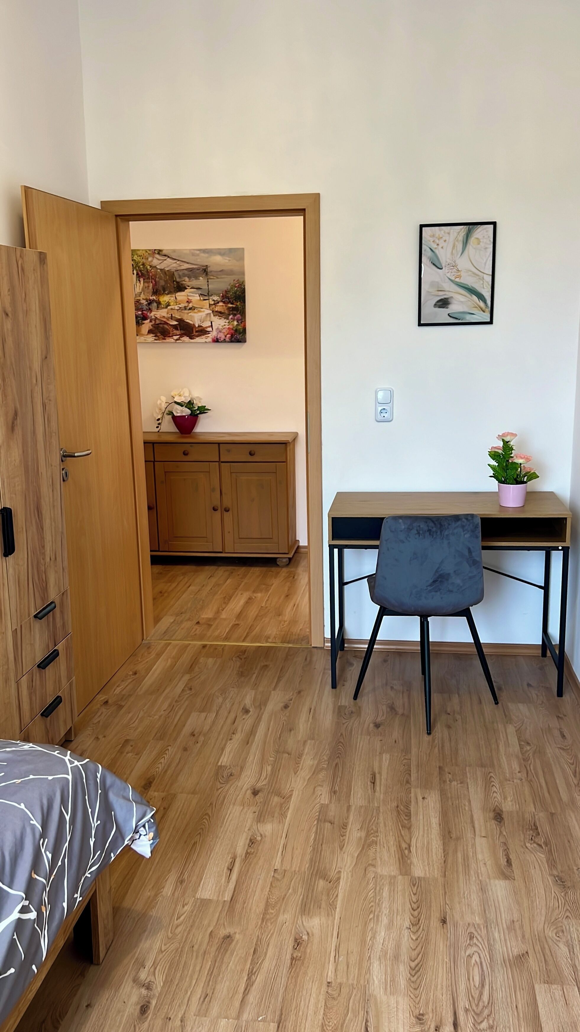 Ein Zimmer mit einem Bett, einem Schreibtisch, einem Stuhl, einem Schrank und einem Bild an der Wand.
