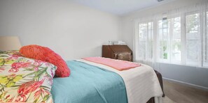 Une chambre à coucher avec un lit, une commode et une fenêtre avec des rideaux.