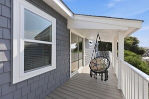 A covered porch with a swing chair and a view of the neighborhood. - Rest Coast Repeat-Just a short walk to the beach! (Atlantic Beach)