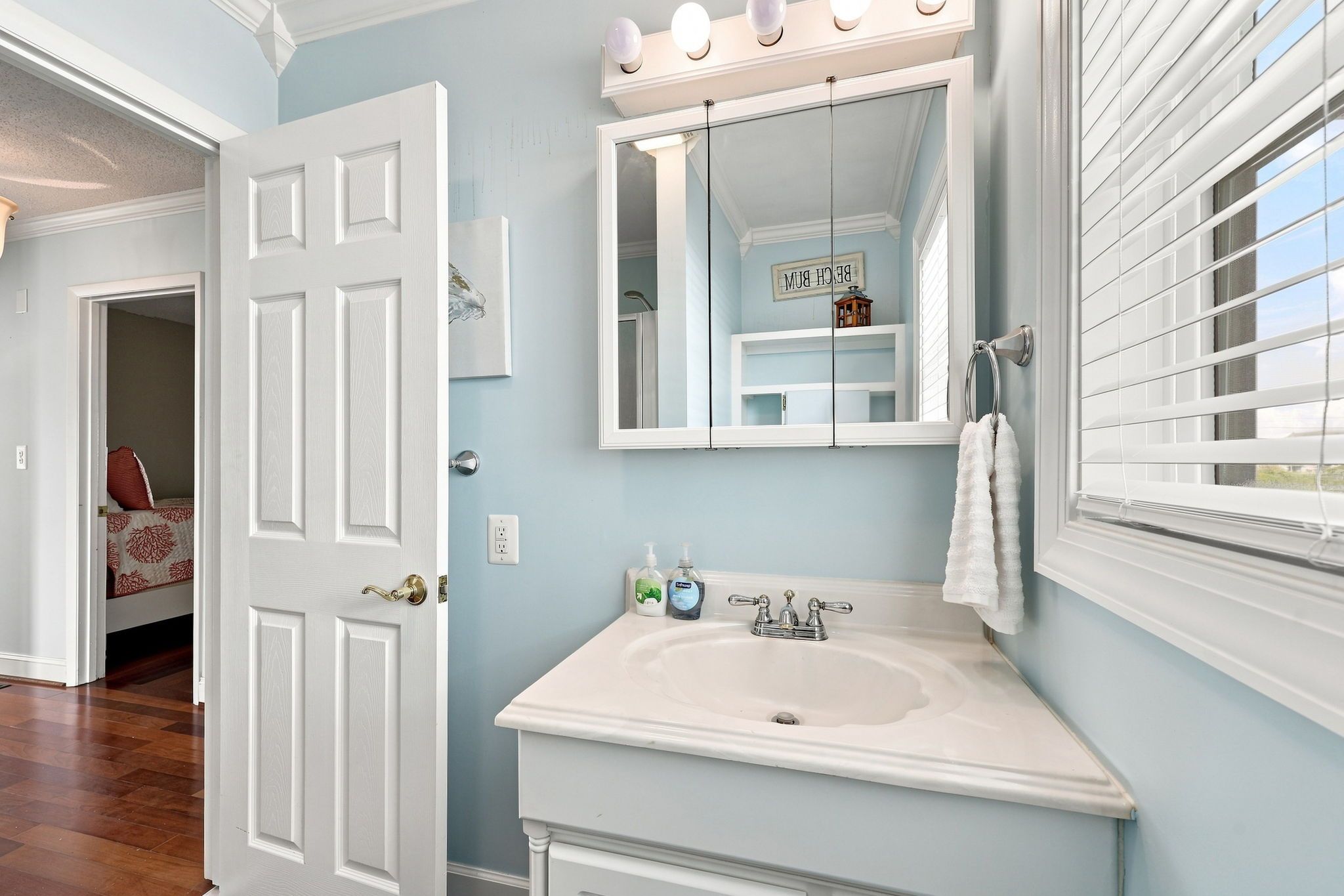 A bathroom with a white sink, a mirror, and a towel rack.