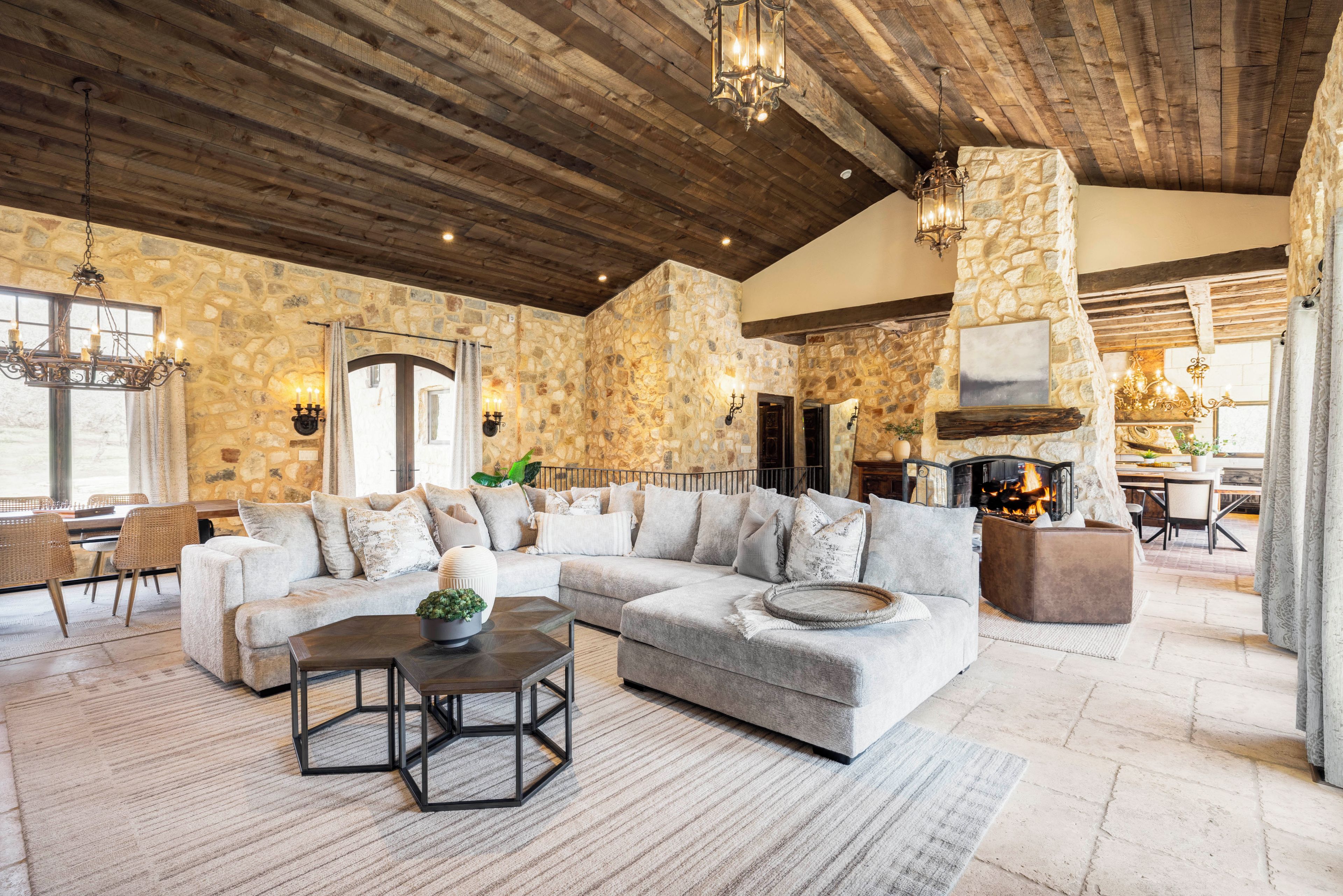 A spacious living room with a stone wall, a large sofa, a fireplace, and a dining area.