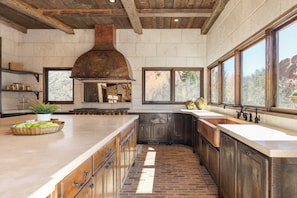 A spacious kitchen with a large island, a built-in oven, and a rustic ceiling.