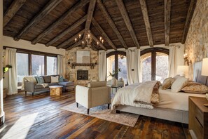 A spacious room with a high wooden ceiling, a large bed, a sofa, and a dining table. - New! Stone Castle Estate in Roxborough State Park (Littleton)