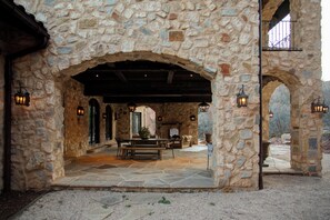 A stone courtyard with a wooden bench and table, stone walls, and lanterns. - New! Stone Castle Estate in Roxborough State Park (Littleton)