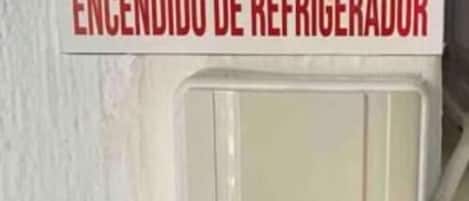 En väggmonterad ljusströmbrytare med en etikett som visar texten ”ENCENDIDO DE REFRIGERADOR” (Kylskåp på).