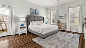 A bedroom with a large bed, two bedside tables, a ceiling fan, and a window with blinds. - Paradise Escape | 3BR Beach Home in Crystal Beach (Destin)