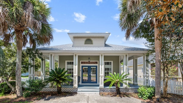 A two-story house with a porch, a blue door, and a white picket fence. - Paradise Escape | 3BR Beach Home in Crystal Beach (Destin)