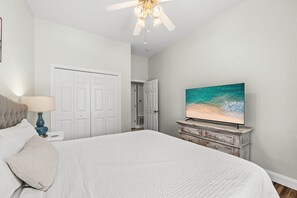 A bedroom with a bed, a nightstand, a lamp, a dresser, and a television. - Paradise Escape | 3BR Beach Home in Crystal Beach (Destin)