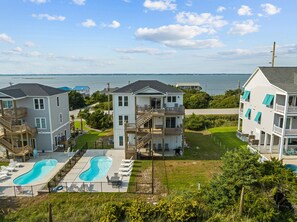 A residential area with a swimming pool, multiple houses, and a view of the water body. - Waverlie’s Watch | Private Pool + Ocean and Sound Views (Emerald Isle)