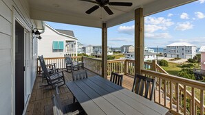 A covered porch with a ceiling fan, wooden deck, and outdoor seating. - Waverlie’s Watch | Private Pool + Ocean and Sound Views (Emerald Isle)