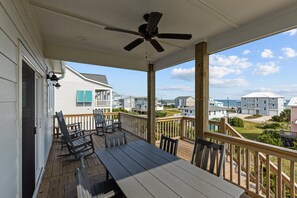 A covered porch with a ceiling fan, wooden deck, and outdoor seating. - Waverlie’s Watch | Private Pool + Ocean and Sound Views (Emerald Isle)