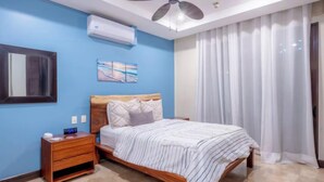 Un dormitorio con cama, mesita de noche y ventilador de techo.