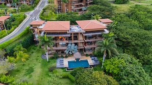 Un hotel de varios pisos con piscina, rodeado de exuberante vegetación.