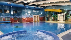 Ein Innenpool mit Whirlpool, Wasserrutsche und Wandgemälden an den Wänden.