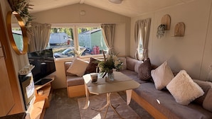 A cozy living area with a sofa, coffee table, and TV, featuring a view of the outside.