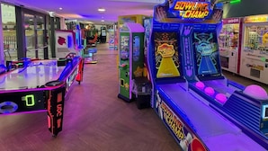 An indoor arcade with various gaming machines, including bowling and claw machines.
