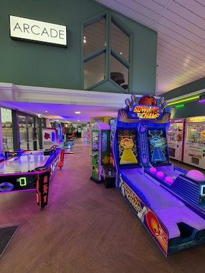 Un salón de juegos interior con diversas máquinas, incluyendo bolos y de pinzas.