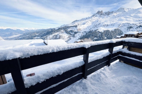 A snow-covered mountain landscape with a wooden fence in the foreground. - Cozy apartment near the ski slopes (Les Allues)