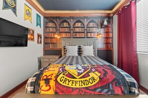 Quarto com edredom temático de Gryffindor, uma estante e uma mesa de cabeceira.