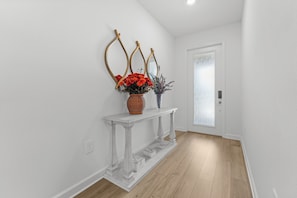A hallway with a white console table, a door with frosted glass, and a light wooden floor. - 5BR Pool & Spa Home with Themed Rooms 376 (KISSIMMEE)