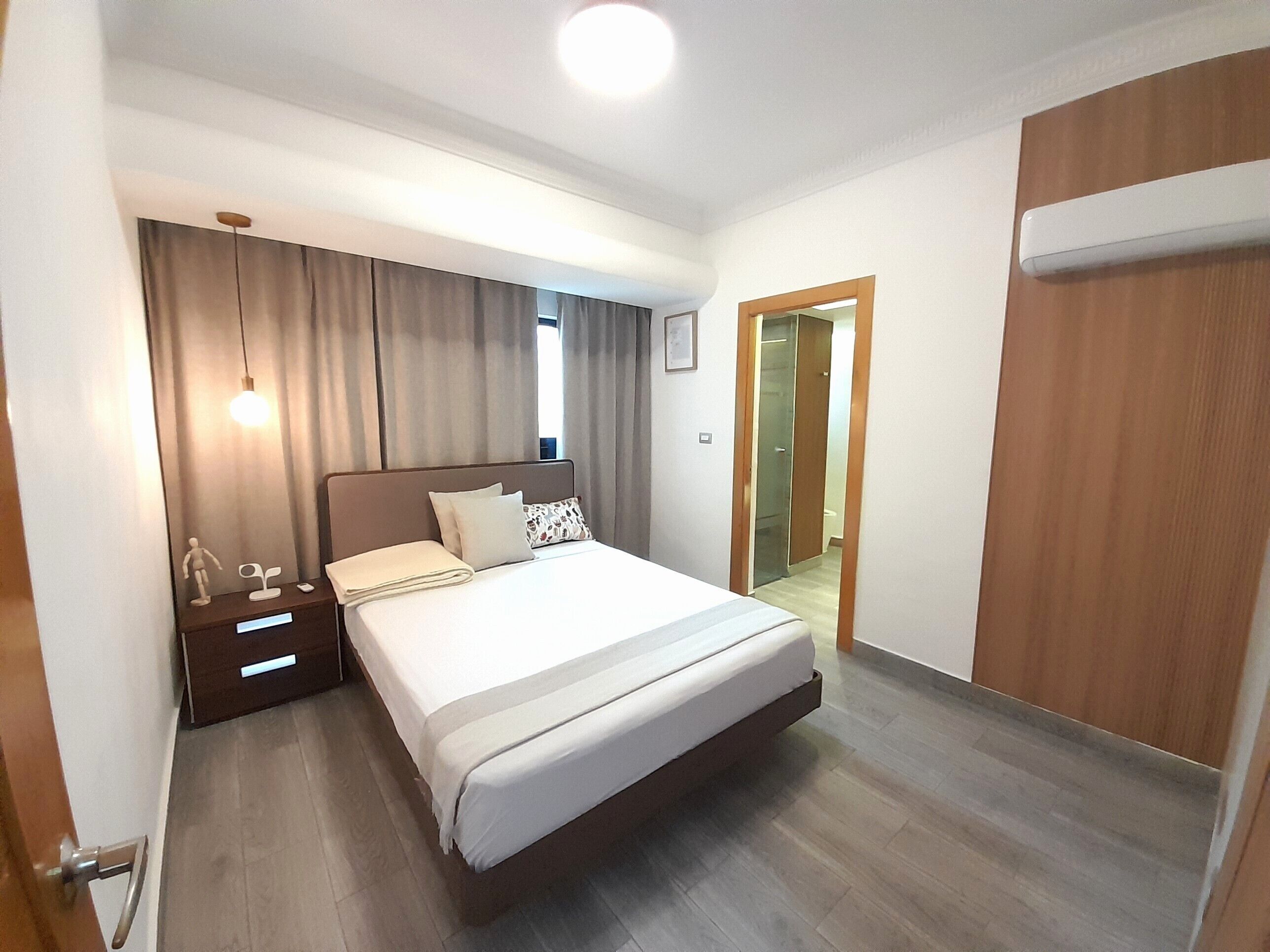 Ein Hotelzimmer mit Bett, Nachttisch, Vorhängen und einer Tür.