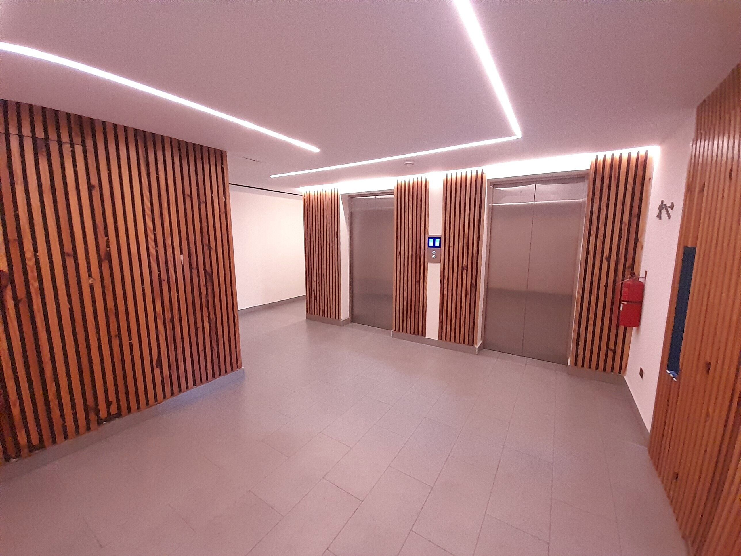 Een modern liftgedeelte met houten lambrisering en een bedieningspaneel.