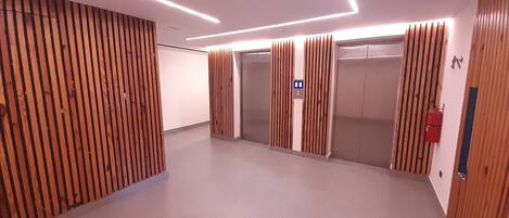 A modern elevator area with wooden paneling and a control panel.