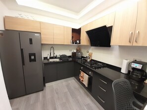 Eine moderne Küche mit einer eingebauten Gaskochstelle, einem Kühlschrank und Holzschränken.