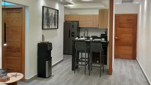 Eine kleine Küche mit Holzschränken, einem Kühlschrank, einem Spülbecken und einer Essecke mit zwei Stühlen.