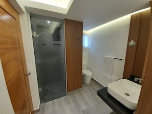 A modern bathroom with a glass shower enclosure, a toilet, and a sink. - Modern and cozy 2-bedroom apartment with AC in the university area Santo Domingo (Santo Domingo)