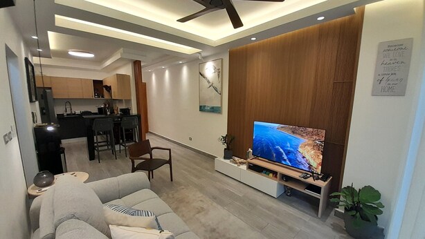 Ein modernes Wohnzimmer mit einer Couch, einem Fernseher und einem Deckenventilator.