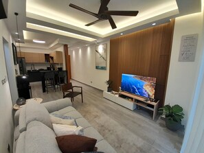 Ein modernes Wohnzimmer mit einer Couch, einem Fernseher und einem Deckenventilator.