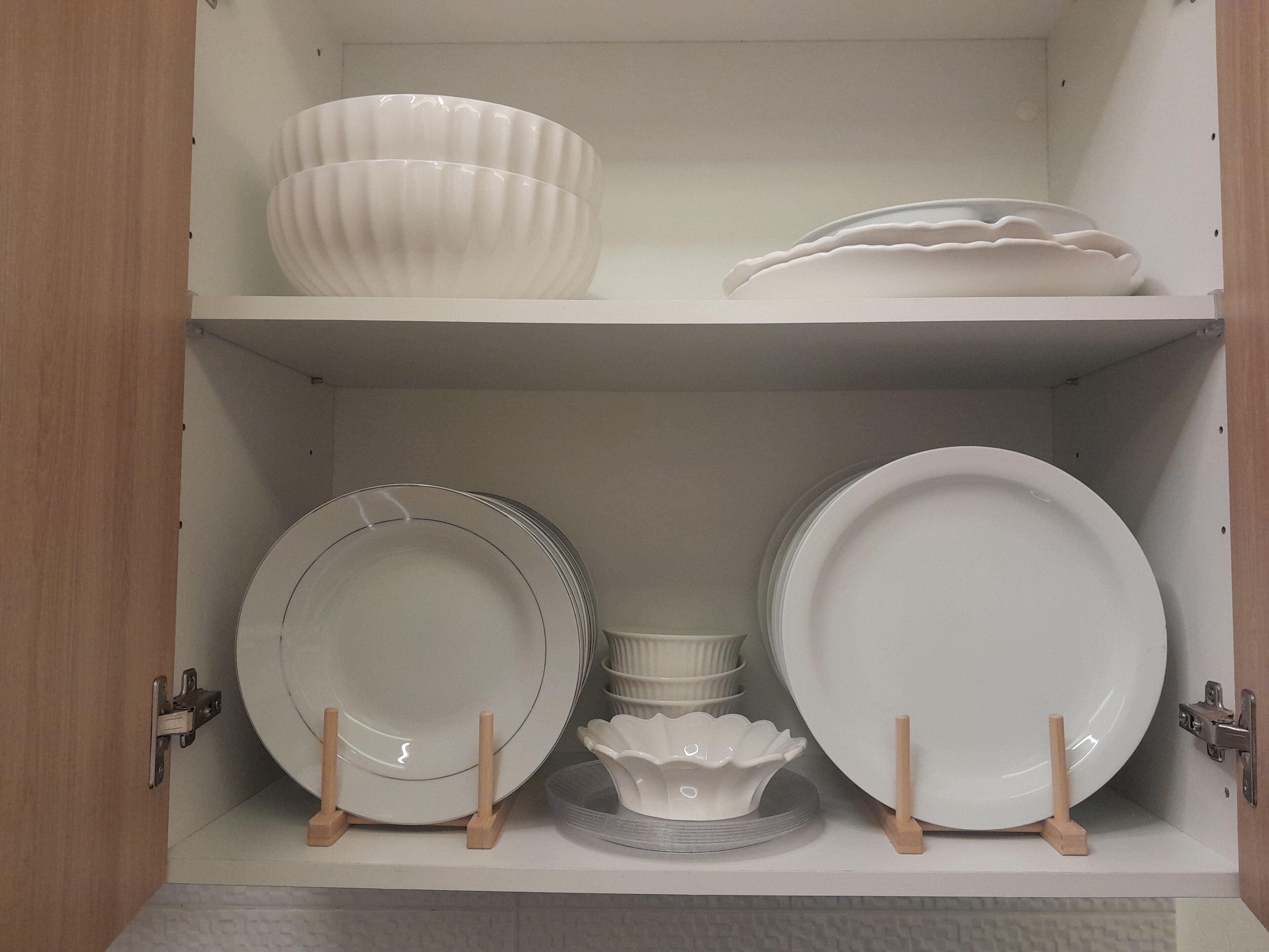 Un mueble con estantes que contiene varios platos y recipientes de cerámica blanca.