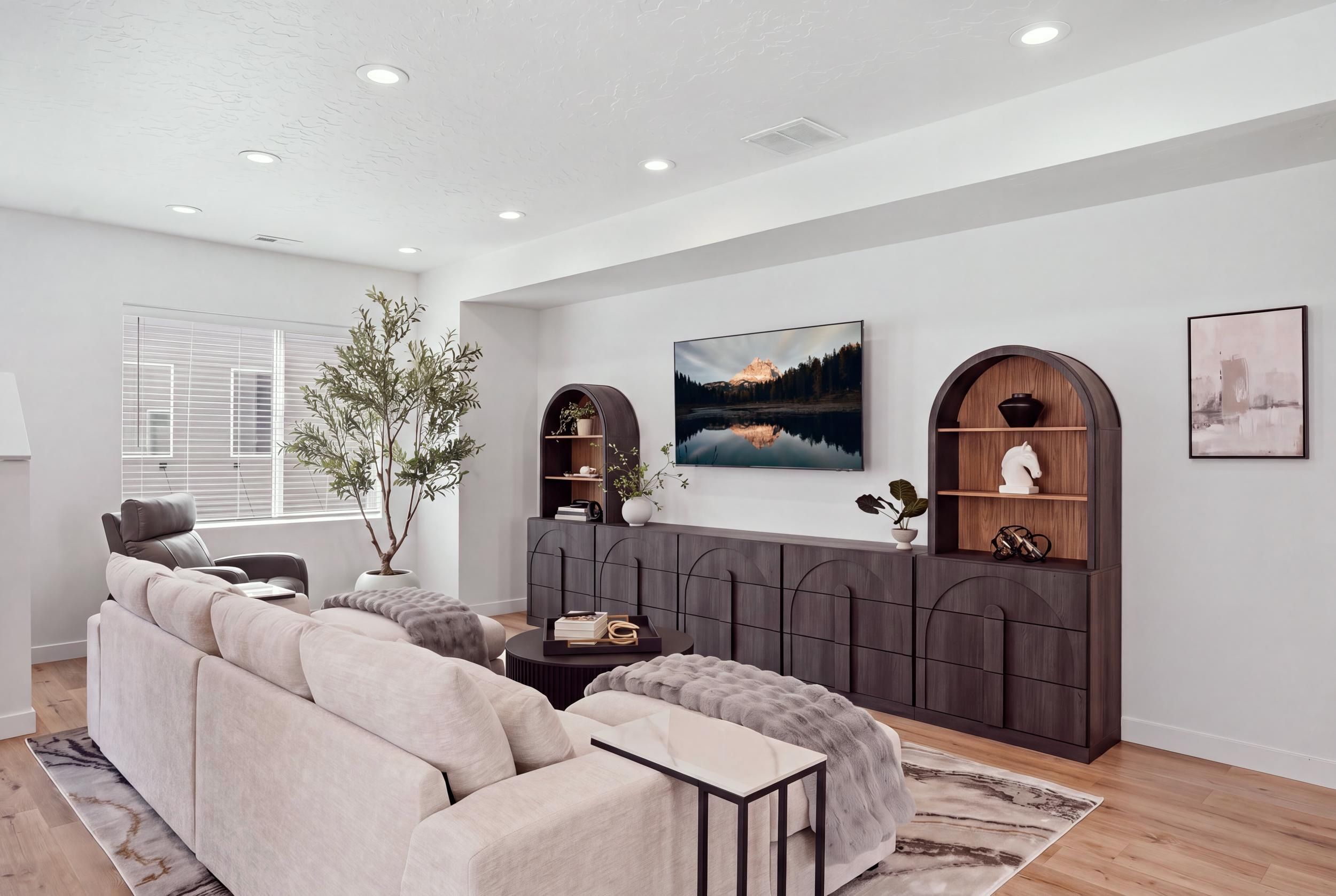 Una sala de estar moderna con un sofá modular, una mesa de centro y un televisor de pantalla plana grande montado en la pared.