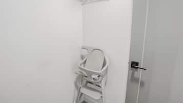 A white door with a silver handle and a white chair with a tray in a corner.