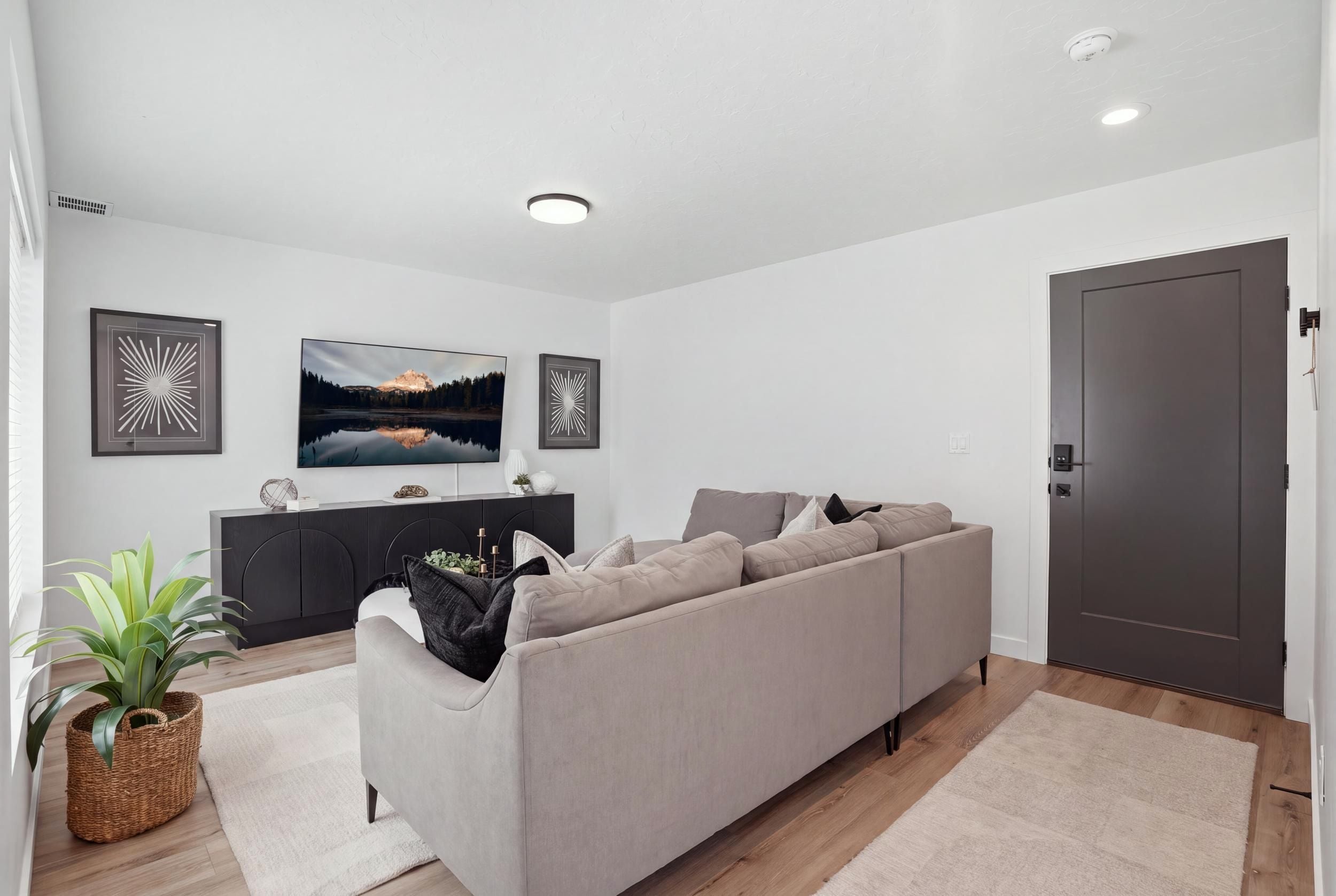 A modern living room with a grey sofa, a flat-screen TV, and two abstract wall art pieces.