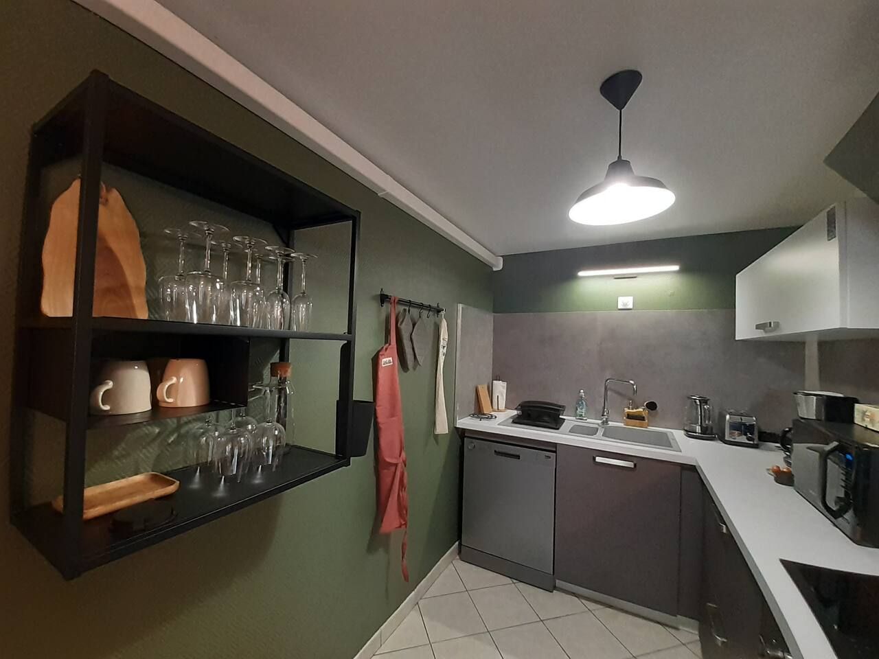 Une cuisine compacte dotée d’une étagère intégrée pour ranger la vaisselle et les verres, d’un petit évier et d’un four à micro-ondes.