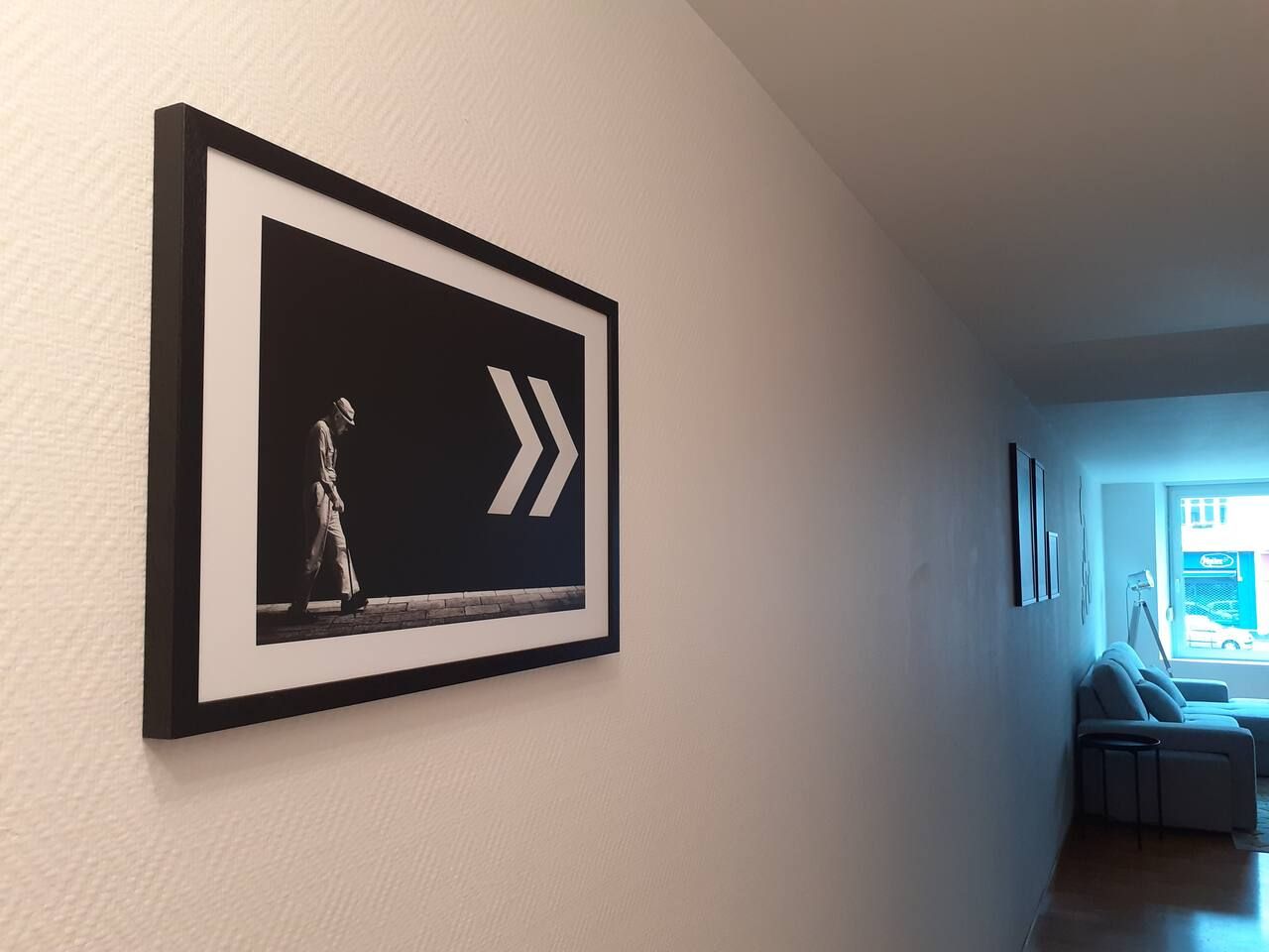 Une œuvre d’art encadrée représentant une figure et des flèches, accrochée à un mur dans un couloir.