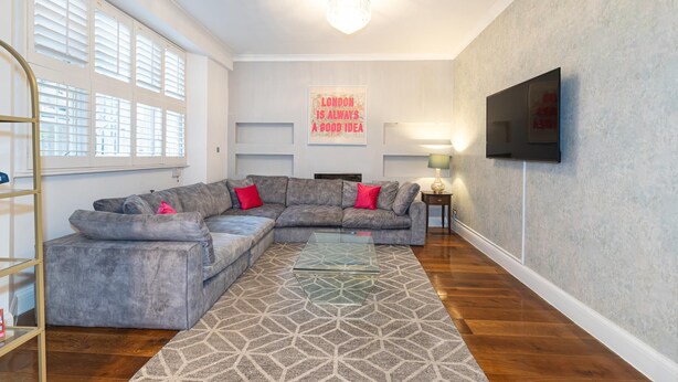 Una sala de estar moderna con un sofá modular, una mesa de centro de vidrio y una alfombra estampada.