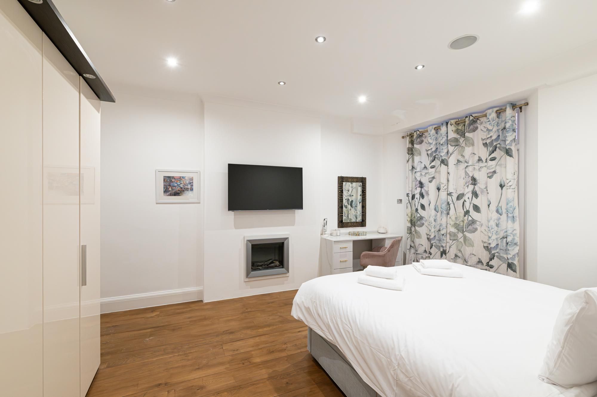 Une chambre à coucher moderne, équipée d’un lit, d’un bureau et d’une télévision.