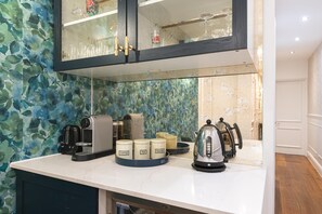 Eine Küche mit Kaffeemaschine, Tee- und Zuckerbehältern sowie einem Wasserkocher auf der Arbeitsfläche.