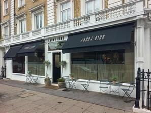 A building with two storefronts, one labeled 'LARRY KING' and the other 'FABBY KING,' featuring outdoor seating with tables and chairs. - Luxurious & Spacious 2 Bed Basement Flat in South Kensington - Pass the Keys (London)