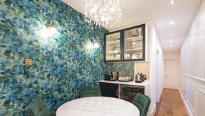 Una cocina moderna con encimera de mármol, sillas tapizadas en verde y una araña.