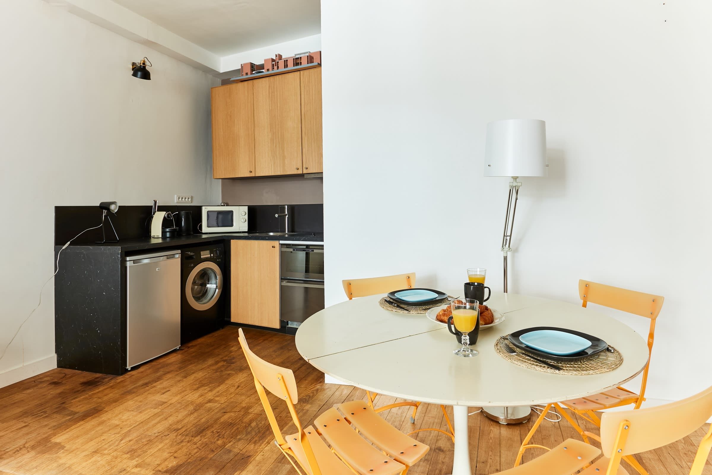 A compact kitchen with wooden cabinets, a washing machine, and a microwave.