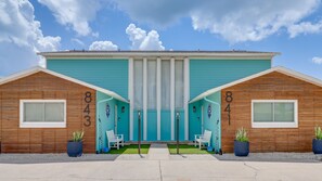 A two-story building with a teal facade, numbered 843 and 841, featuring a central entrance with a door and two windows on each side. - A-Wave for Everyone - Full duplex + 2 Pools! (New Smyrna Beach)