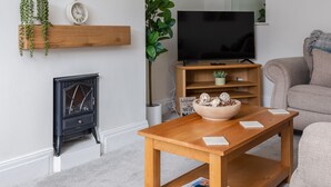 Ein modernes Wohnzimmer mit Kamin, Fernseher, Couchtisch und Sofa.