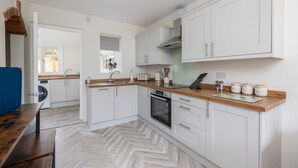 Eine moderne Küche mit weißen Schränken, einer Holz Arbeitsplatte und einem eingebauten Backofen.