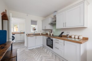 Una cocina moderna con muebles blancos, encimera de madera y horno empotrado.