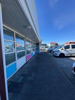 A parking lot with several cars parked in front of a building with large windows and a flat roof.